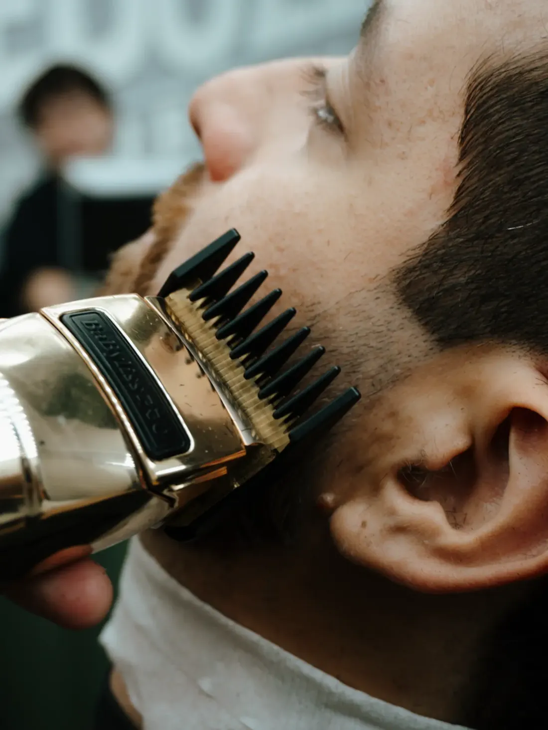 Máquina com pente definindo a linha da barba na lateral do rosto